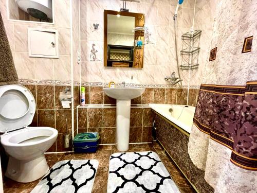 a bathroom with a toilet and a sink and a tub at Apartments on Kuban 63 in Pavlodar