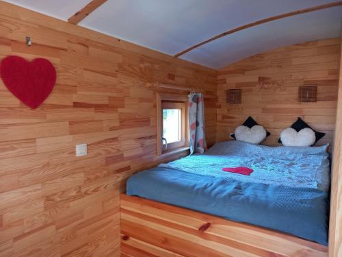 a bedroom with a blue bed in a wooden wall at Camping des Saules in Jurbise