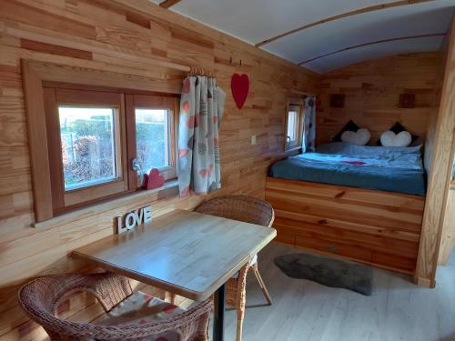 Cabaña de madera con mesa y cama en Camping des Saules en Jurbise