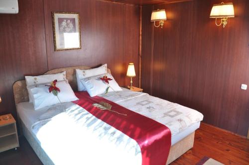 a bedroom with a large bed with a red blanket on it at Hotel Brod Panini Veles in Veles