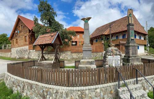 a wooden fence in front of a house with a building at Székelyföld ,Siklódi Kő Vendégház, Tornácosház in Bartoştana