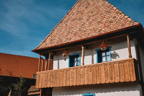 ein Haus mit einem Holzbalkon und 2 Fenstern in der Unterkunft Székelyföld ,Siklódi Kő Vendégház, Tornácosház in Bartoştana