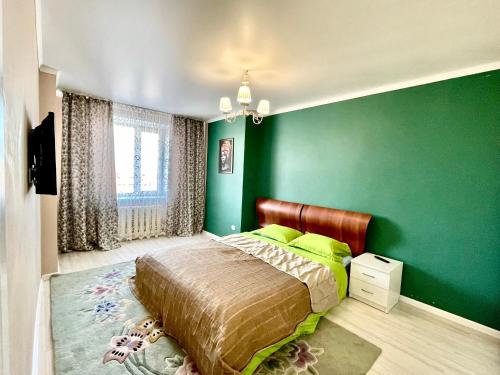 Dormitorio verde con cama y pared verde en 4х комнатные апартаменты, en Pavlodar