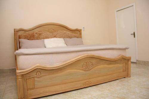 a bed with a wooden frame in a room at Masbella Hotel Ltd 