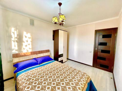 Schlafzimmer mit einem Bett mit blauen Kissen und einem Kronleuchter in der Unterkunft 2х комнатные апартаменты рядом с Центральной Мечетью in Pawlodar