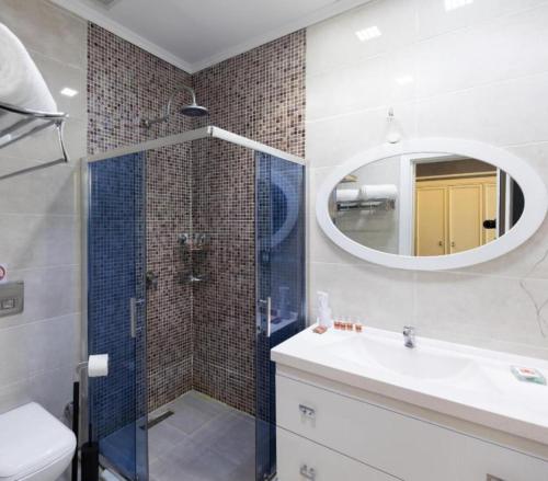 ein Bad mit einer Dusche, einem Waschbecken und einem Spiegel in der Unterkunft Dondar Hotel Formula 1 View in Baku