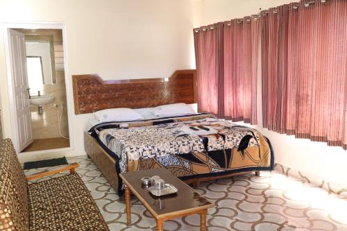 um quarto com uma cama e uma mesa num quarto em Hotel Sri Balaji em Ooty