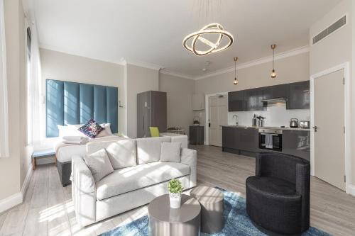 uma sala de estar com um sofá e uma cadeira e uma cozinha em Air Conditioned Apt High St Kensington em Londres