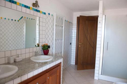Baño con 2 lavabos y espejo en Casa Vacanza Le Fresie, en Nuoro