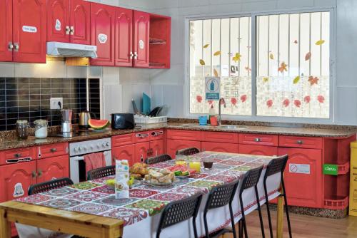 una cocina con armarios rojos y una mesa con comida. en Meiga Backpackers Hostel, en Santiago de Compostela