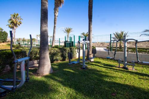 a park with a bunch of swings and palm trees at ESPACIO 5 - Primera Línea de Playa in Cullera