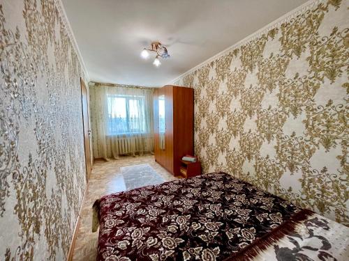um quarto com uma cama num quarto com papel de parede em Квартира в центре Павлодара em Pavlodar