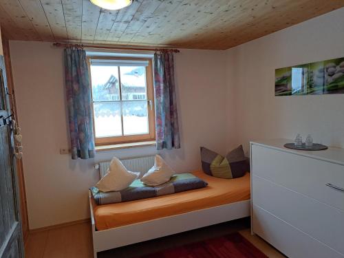 a small room with a bed with a window at Ferienwohnung Annele in Hittisau