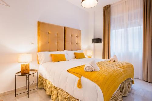 a bedroom with a large bed with a yellow blanket at Apartamentos Cruz de San Andrés in Seville