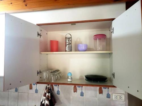 una cocina con armarios blancos con utensilios. en Excelente departamento tranquilo en Ushuaia