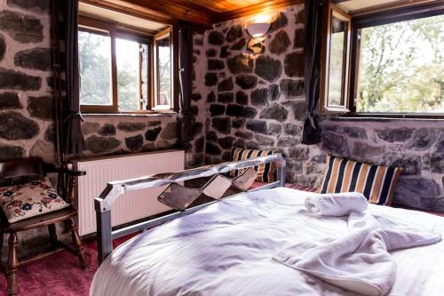 Bett in einem Zimmer mit einer Steinmauer in der Unterkunft Πέτρινη κατοικία με υπέροχη θέα στο όρος Κόζιακα. 