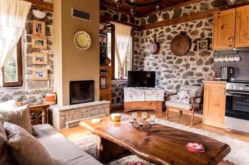 a living room with a table and a stone wall at Πέτρινη κατοικία με υπέροχη θέα στο όρος Κόζιακα. in Longiaí