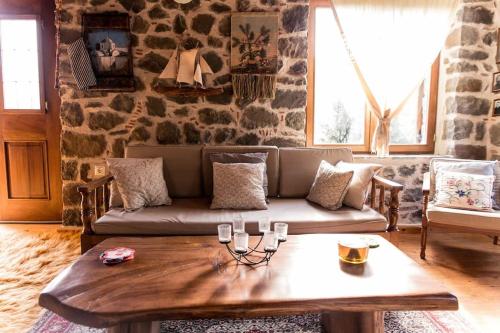 a living room with a couch and a coffee table at Πέτρινη κατοικία με υπέροχη θέα στο όρος Κόζιακα. in Longiaí