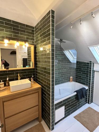 une salle de bain avec une baignoire, un lavabo et un miroir dans l'établissement Maison chaleureuse à Trouville-sur-Mer avec vue sur la ville, à Trouville-sur-Mer