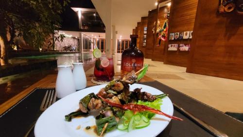 a plate of food on a table with a bottle of wine at Arachchi Heritage in Anuradhapura
