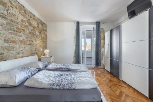a bedroom with a large bed and a brick wall at Penthouse Lorena in Poreč