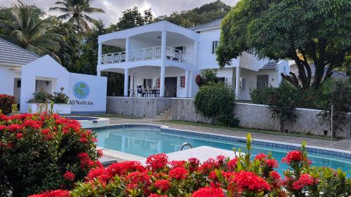a view of a house with a swimming pool and flowers at All Nations Guest House in Port Antonio