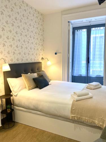 a bedroom with a large white bed with a window at Apartamentos Fuencarral in Madrid