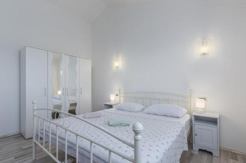 biała sypialnia z białym łóżkiem i lustrem w obiekcie Holiday Home Bianca w mieście Novigrad