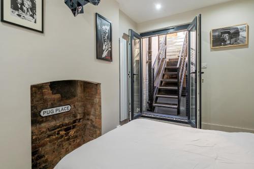 a bedroom with a bed and a brick fireplace at Period 3-Bed Maisonette next to the City of London in London