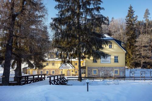 阿德爾什帕赫的住宿－Skalní Mlýn Adršpach，一座黄色的大建筑,雪中设有栅栏