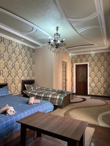 um quarto com duas camas, uma mesa e um lustre em ALI HOSTEL em Dushanbe