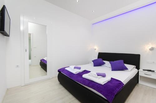 1 dormitorio con cama con almohadas moradas y espejo en Apartment Borovac, en Vrgorac