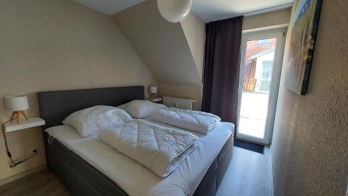 a bedroom with a bed with white sheets and a window at Ferienwohnung Ostsee-Buhne Baabe in Baabe