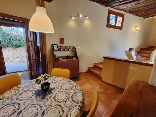 uma sala de jantar com uma mesa e uma pessoa num computador portátil em Casas Rurales El Parador em Letur