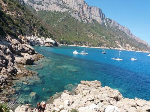 a group of boats in the water near a mountain at Dommu Biddasusu in Baunei