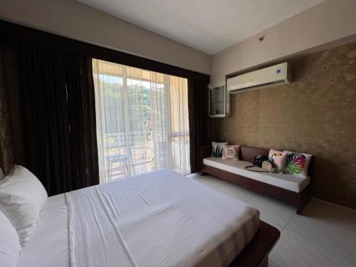 a bedroom with a large white bed and a window at Bonel condo at Pico de Loro in Cutad
