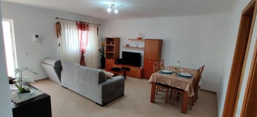 ein Wohnzimmer mit einem Sofa und einem Tisch in der Unterkunft Cabana Formosa T2 Férias Cabanas de Tavira in Cabanas de Tavira