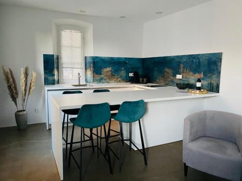 a kitchen with a bar with three chairs and a sink at Rotmain Apartments in Bayreuth