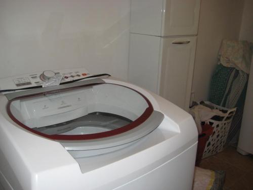 een witte wasmachine in een keuken met een koelkast bij QUARTO COM BANHEIRO PRIVATIVO in Sao Paulo