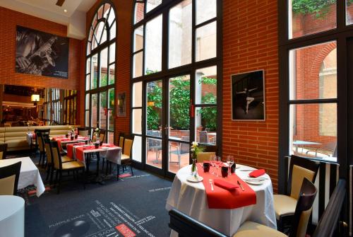 ein Esszimmer mit Tischen, Stühlen und Fenstern in der Unterkunft Plaza Hotel Capitole Toulouse - Anciennement-formerly CROWNE PLAZA in Toulouse