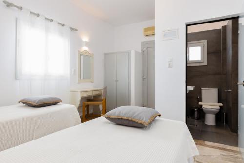 a white room with two beds and a bathroom at Roses Beach in Parikia