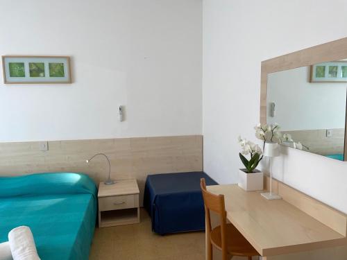 Habitación con cama, mesa y espejo. en Pensione Ornella en Lignano Sabbiadoro
