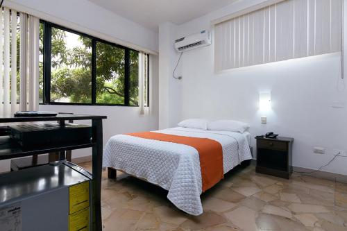 a white bedroom with a bed and a window at Hotel de Alborada in Guayaquil
