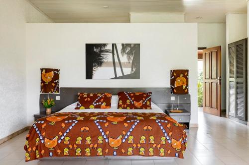 1 dormitorio con 1 cama grande con almohadas de color naranja en Hotel Coucoue Lodge, en Assinie