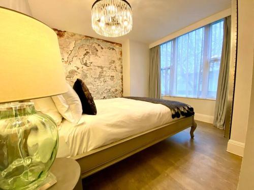 een slaapkamer met een bed met een lamp en een raam bij Elegant Apartment - 1 Minute walk to Poole Quay - Great Location - Free Parking - Fast WiFi - Smart TV - Newly decorated - sleeps up to 2! Close to Poole & Bournemouth & Sandbanks in Poole