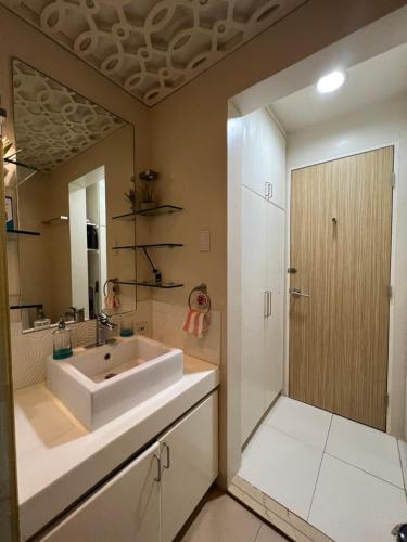 ein Badezimmer mit einem weißen Waschbecken und einem Spiegel in der Unterkunft Bonel condo at Pico de Loro in Cutad