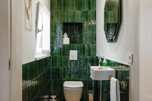 Baño de azulejos verdes con aseo y lavamanos en HomeThirtyFour, en Verona