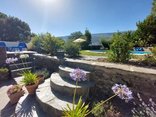 a garden with stairs and flowers and a pool at Casa de Alguaztar in Bubión