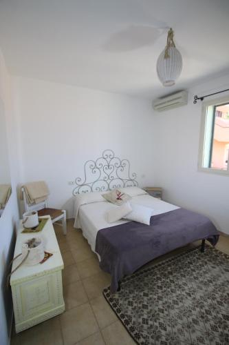 een witte slaapkamer met een bed en een tafel bij Appartamento La Conchiglia in Palau