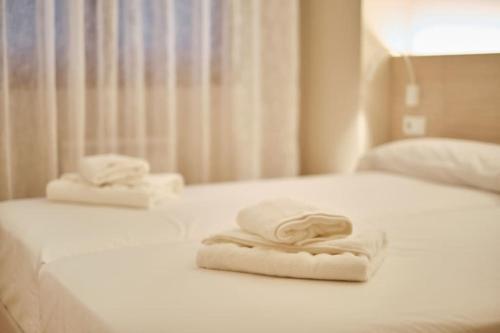 2 toallas sentadas encima de una cama blanca en Yuhom, casas con alma. Xacedos 5, en Miño